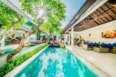 an indoor pool with palm trees in a house at Villa Olli in Seminyak