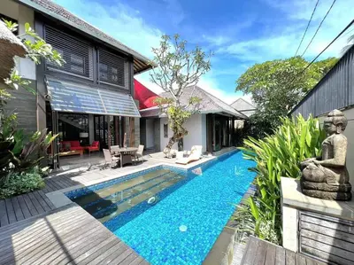 a swimming pool in front of a house with a garden at Villa Canthy@Seminyak in Seminyak