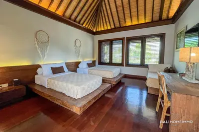 two beds in a room with wooden floors and windows at Villa Canthy@Seminyak in Seminyak