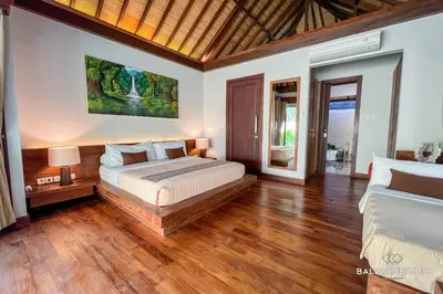a bedroom with a large bed and wooden floors at Villa Canthy@Seminyak in Seminyak