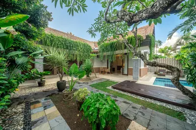 a garden with a swimming pool and a house at Nameera Villa in Seminyak