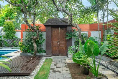 a house with a wooden door in a garden at Nameera Villa in Seminyak