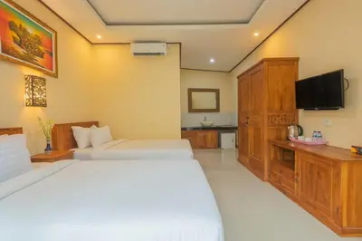 a hotel room with two beds and a television at Liliy Guest House Kuta in Legian