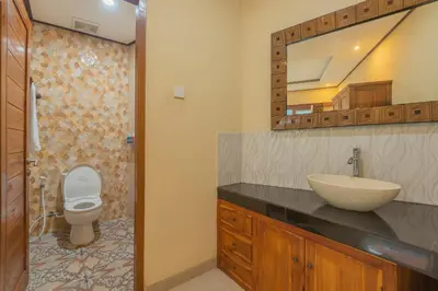 a bathroom with a sink and a toilet and a mirror at Liliy Guest House Kuta in Legian