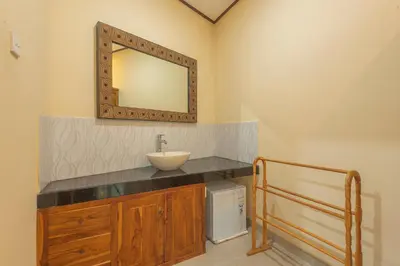 a bathroom with a sink and a mirror on the wall at Liliy Guest House Kuta in Legian