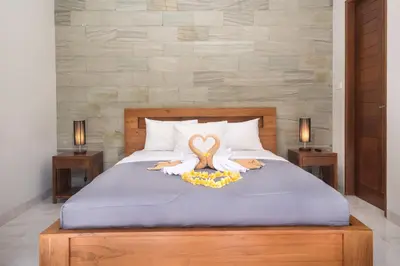 a bed with two swans on it with two lamps at Vpas Villa in Seminyak