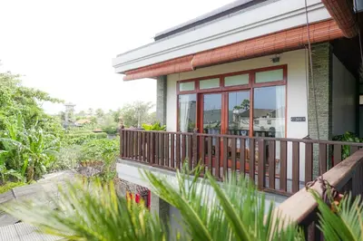 a house with a wooden balcony with a window at Tropical Beach House Bali in Seminyak