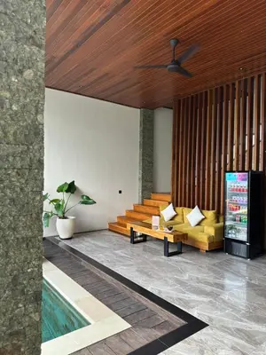 a living room with a pool and a ceiling fan at Tropical Beach House Bali in Seminyak
