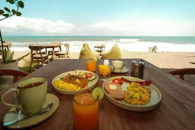 a wooden table with plates of food on the beach at Tropical Beach House Bali in Seminyak