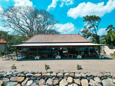 a building on the beach with chairs and tables at Tropical Beach House Bali in Seminyak