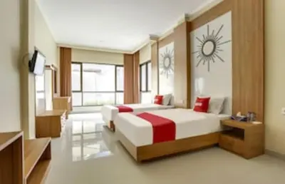 a bedroom with two beds and a clock on the wall at Moreno Homestay in Legian