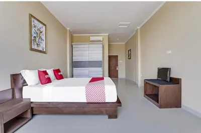 a bedroom with a large bed and a television at Moreno Homestay in Legian