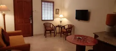 a living room with a table and chairs and a television at Club Bali Suite Legian in Legian