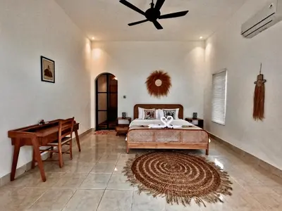 a bedroom with a bed with a ceiling fan and a table at Villa Curves Bali in Seminyak