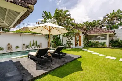 a backyard with two chairs and an umbrella at Villa Curves Bali in Seminyak