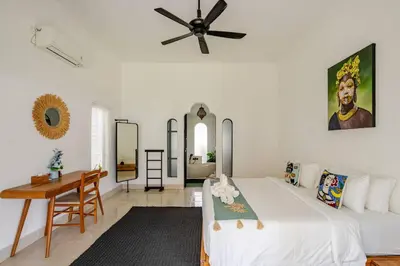 a bedroom with a bed and a desk and a ceiling fan at Villa Curves Bali in Seminyak