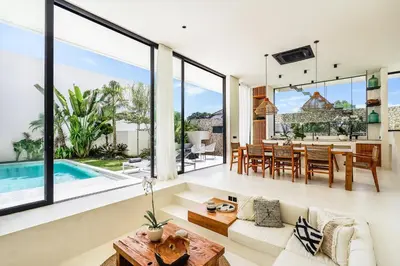 an open living room and dining room with large windows at Casa Umalas Villa by Betterplace in Canggu