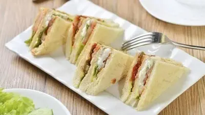 two sandwiches on a white plate with a fork at 9 Residence's Seminyak in Seminyak
