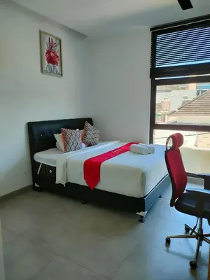 a bedroom with a bed and a chair and a window at Milo Modern Five-Bedrooms Villa in Jimbaran