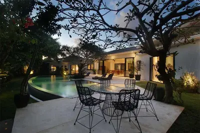 a patio with a table and chairs next to a pool at Villa Papaya by Optimum Bali Villas in Canggu